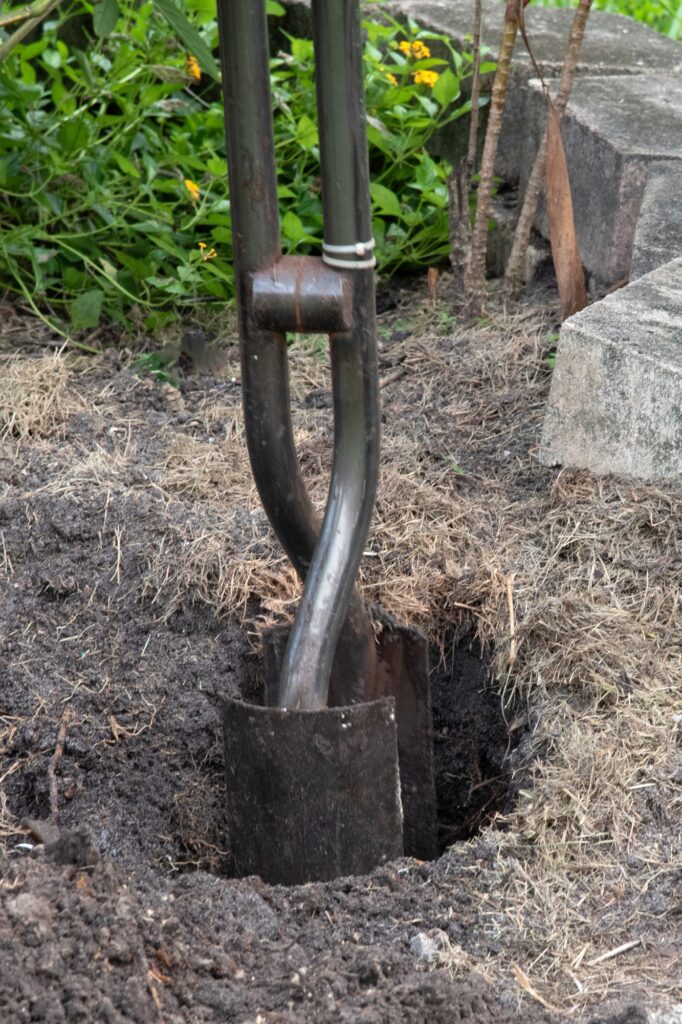 homeowner using a clamshell post hole digger to dig a fence post hole
