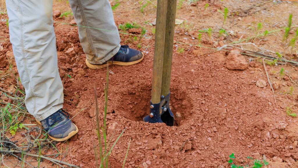 post hole dug in a grassy lawn showing correct depth for a fence post