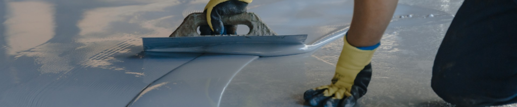 person applying epoxy coating to fix garage floor problems with trowel
