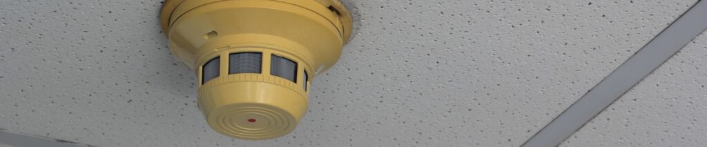 yellow smoke detector on ceiling showing why do smoke detectors turn yellow with age