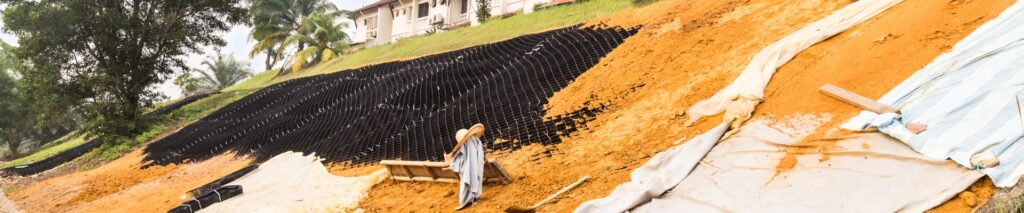 how to fix erosion on a slope — erosion control fabric being installed on a steep residential slope