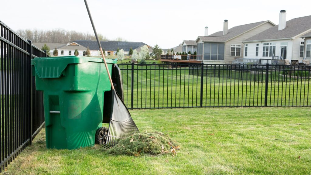 large pile of thatch debris raked from lawn next to a trash bin