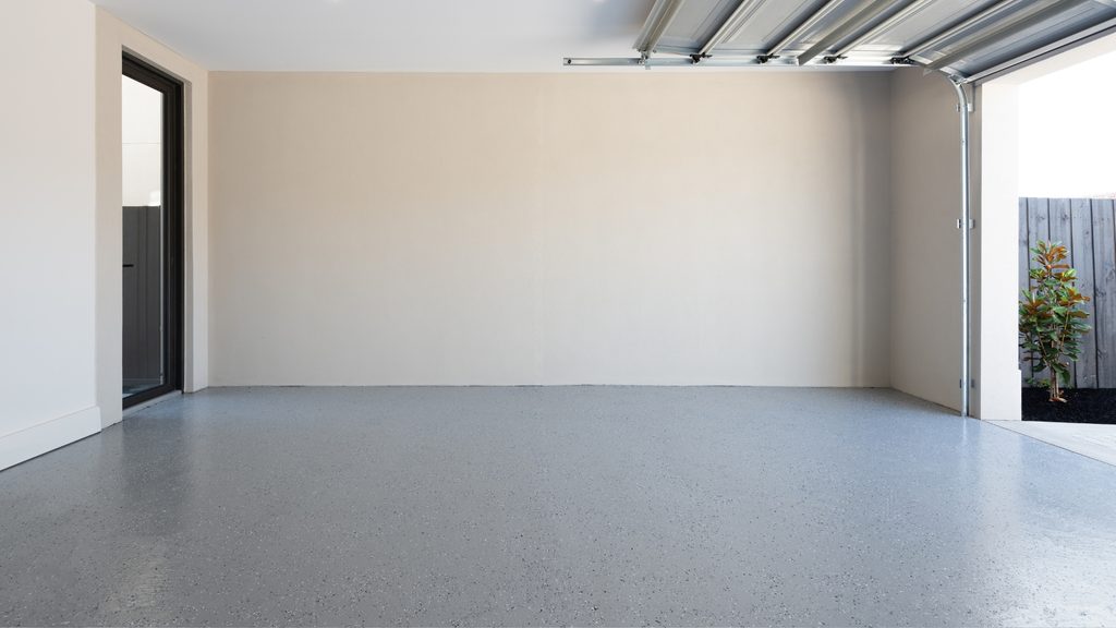 Empty garage with a clean sealed gray epoxy floor and open garage door showing the finished result