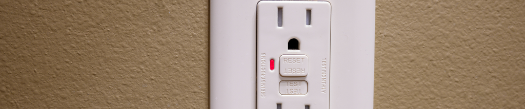 GFCI outlet with test and reset buttons on a tan textured wall. How to test a GFCI outlet