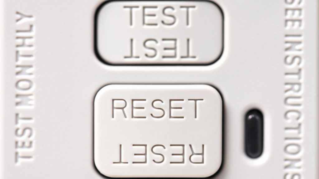 close-up of GFCI outlet test and reset buttons with test monthly label