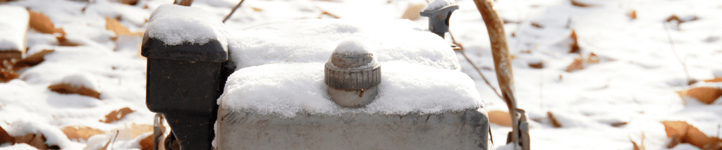 red push lawn mower left outside covered in snow and fallen leaves. How to winterize a lawn mower