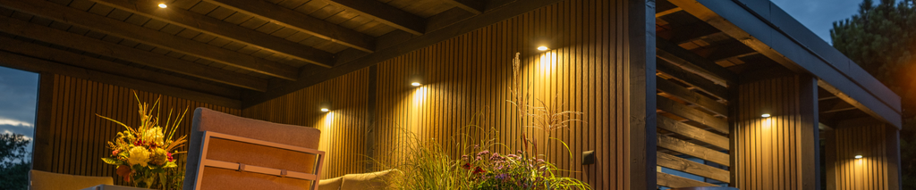 warm outdoor patio lighting illuminating wood siding and outdoor furniture at night. Outdoor lighting on a budget
