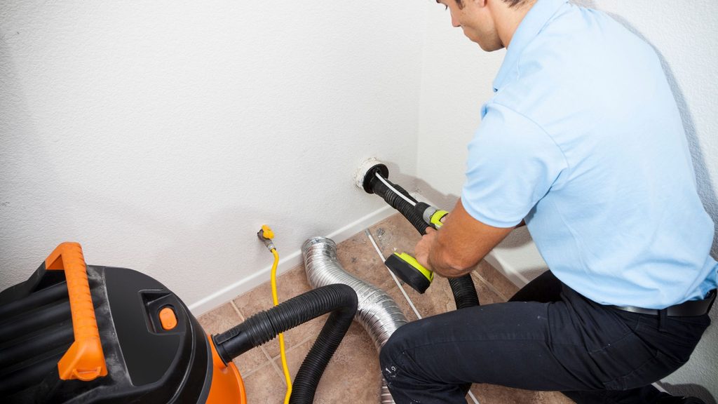 Professional technician using a shop vac and cleaning tools to clean a dryer vent