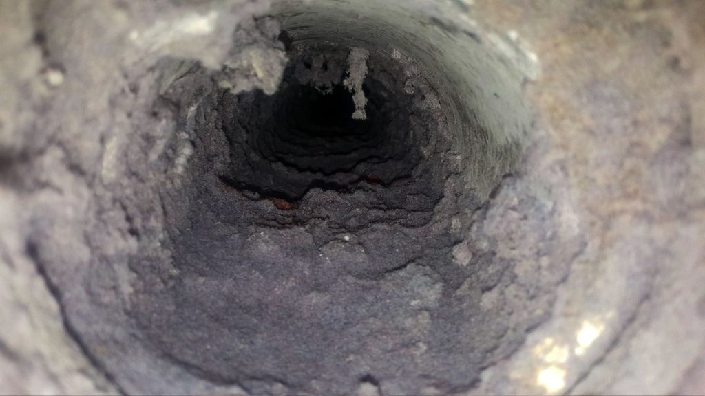 Interior view of a severely clogged dryer vent duct showing dangerous lint accumulation