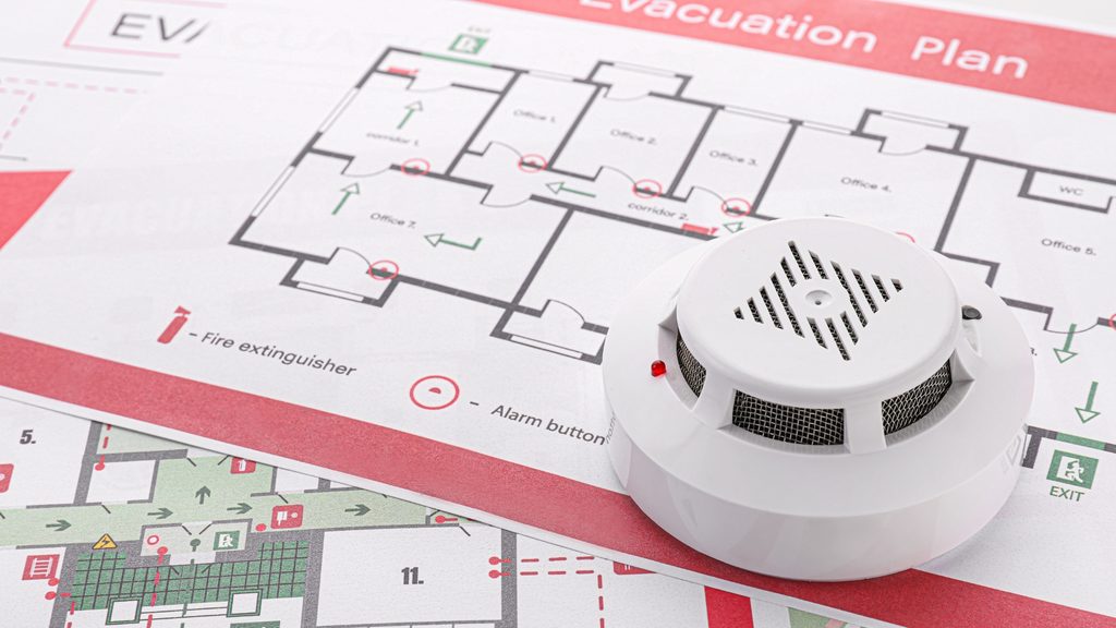 Smoke detector resting on a printed home fire evacuation plan
