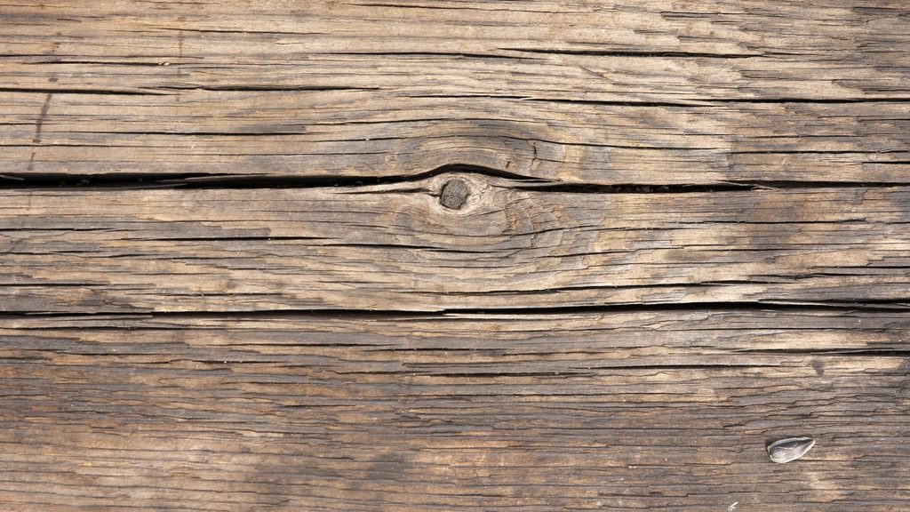 Weathered gray wood deck boards with visible cracks and surface wear before cleaning and restoration
