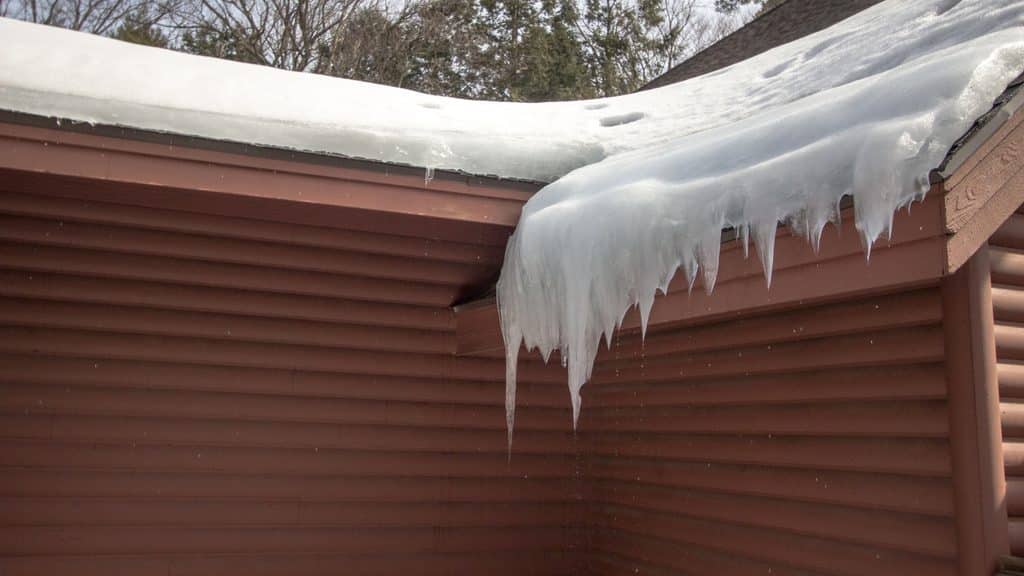 Ice dam forming a thick ridge of ice along the edge of a snowy roof