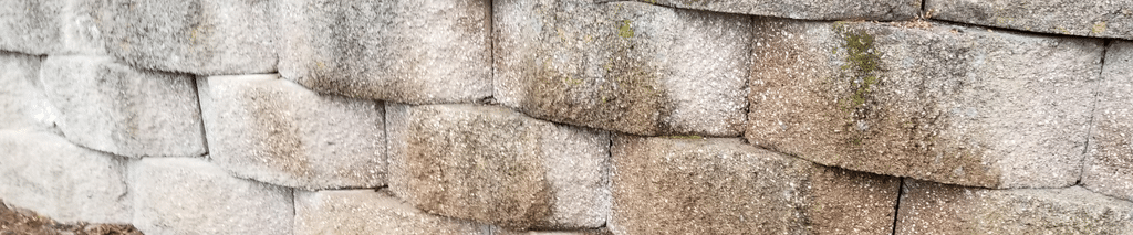 Concrete block retaining wall with caps holding back a planting bed. Retaining wall calculator