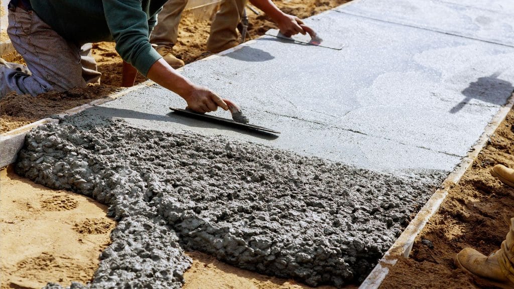 smoothing a fresh concrete walkway with a trowel